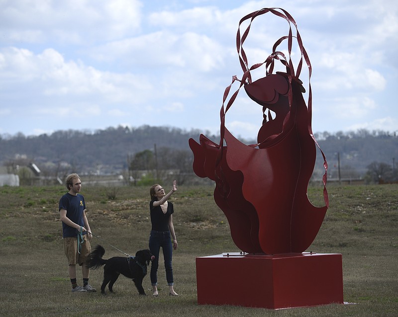 Eve Hermann and Nick York walk their dog, Caboose, through the Sculpture Fields at Montague Park in February.