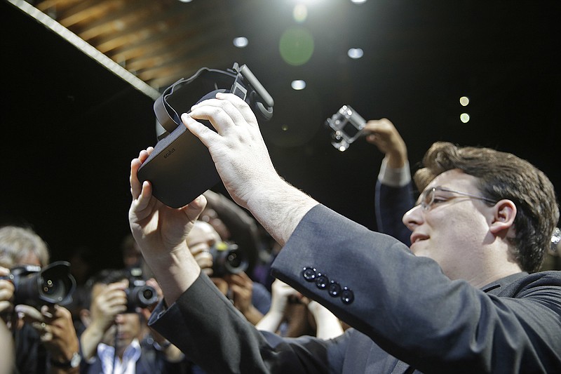 
              FILE - In this June 11, 2015 file photo, Oculus founder Palmer Luckey holds up the new Oculus Rift virtual reality headset for photographers following a news conference in San Francisco.  Luckey is leaving the company. Facebook did not give a reason for Luckey’s departure. His last day is Friday, March 31, 2017. (AP Photo/Eric Risberg)
            