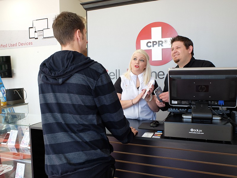 Kalyn Cook, center, and Ryan Cook show Nathan Dodd the benefits of a cell phone accessory Wednesday at CPR-Cell Phone Repair on N. Market Street. "CPR is the largest repair franchise in the world," Cook said. "We have a full time tech, Caleb Burris, and we repair phones, tablets and computers with buy, sell and trade options."
The store is scheduled to offer drone repair in two to four weeks, according to Cook.