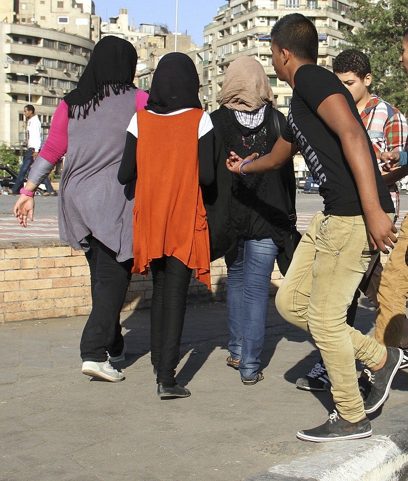 
              FILE -- In this Oct. 28, 2012 file photo, a youth reaches out as young girls walk past near Tahrir Square, Cairo, Egypt. Hundreds of Egyptian women and girls have come out to denounce sexual harassment and share personal stories about it on social media, breaking a taboo and raising the ire of the country’s conservative majority. In posts on Facebook and Twitter from the weekend to Wednesday, rare, candid stories focused on women’s first experiences of harassment, almost all of which occurred in childhood and some involving family members and teachers. (AP Photo/ Mohammed Abu Zeid, File)
            