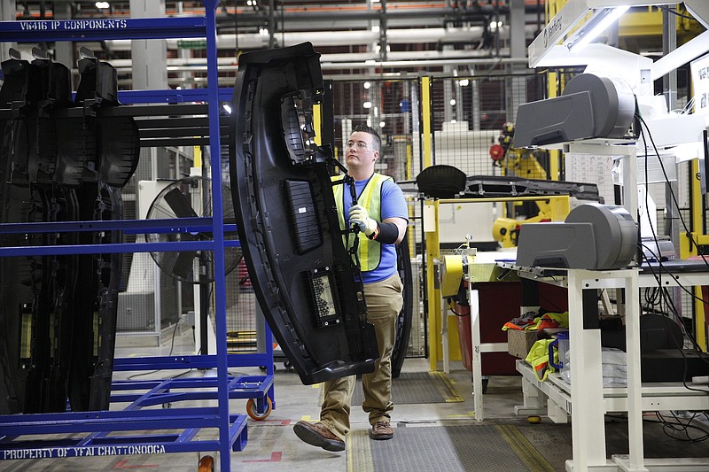 A worker removes auto parts from an injection molding station during an open house at the new Yanfeng Automotive Interiors manufacturing plant on Thursday, Jan. 19, 2017, in Chattanooga, Tenn. The manufacturer provides interior parts for Volkswagen vehicles.