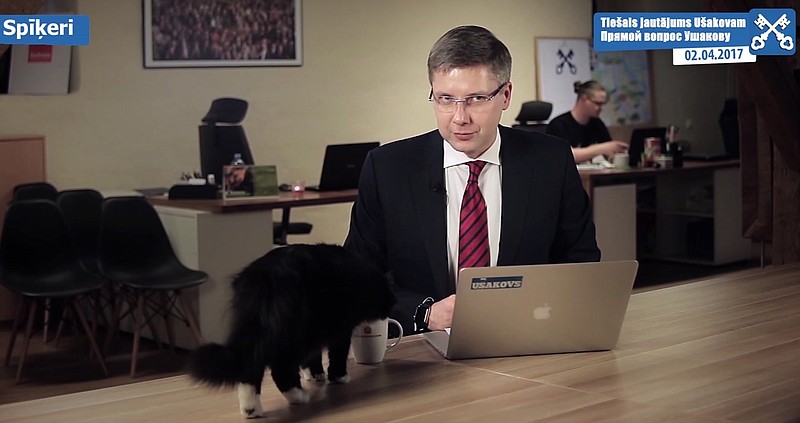 
              The Mayor of Riga Nils Usakovs looks up as his cat Dumka drinks from his cup while the mayor recording a video that was aired on Sunday April 2, 2017.  Usakovs was talking about the city's efforts to fix potholes during his weekly online question-and-answer show when he got interrupted by his cat Dumka. (Nils Usakovs via AP)
            