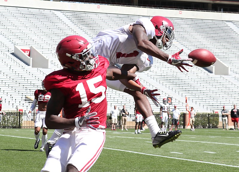 Senior receiver Robert Foster (1) reaches for the ball as junior safety Ronnie Harrison (15) defends during Saturday's first spring scrimmage in Tuscaloosa.