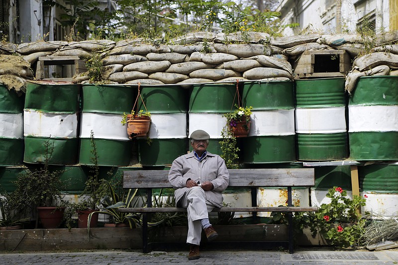 
              An elderly man sit on a bench in front of the barrels and sandbags blocking a road crossing from the south, Greek Cypriot, to the north, Turkish Cypriot breakaway controlled areas in the divided capital Nicosia, Cyprus, Monday, April 10, 2017. Talks aimed at reunifying ethnically divided Cyprus resume after a two-month halt. But negotiations face difficult challenges with the island's Greek Cypriot president accusing the breakaway Turkish Cypriot leader of backpedaling on key issues at Turkey's prompting after months of solid progress. Cyprus was split in 1974 when Turkey invaded following a coup mounted by supporters of union with Greece. (AP Photo/Petros Karadjias)
            