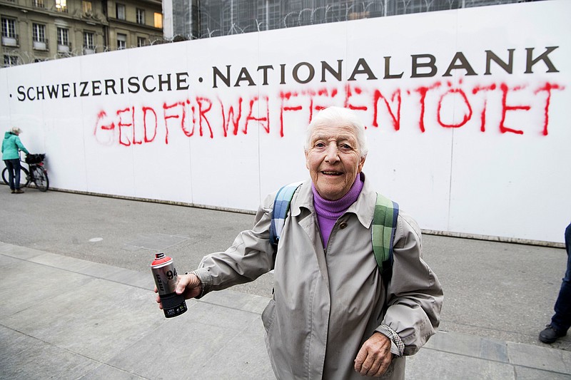 
              86-year-old activist Louise Schneider poses for media after spraying the words "Money for Weapons Kills" (in German "Geld Fuer Waffen toetet") on a wall of the Swiss National Bank in Bern, Switzerland, Tuesday, April 11, 2017, as part of a campaign to strip state financing for arms vendors. (Anthony Anex/Keystone via AP)
            
