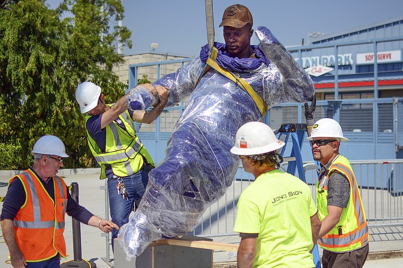 In this April 10, 2017, photo provided by the Los Angeles Dodgers, workers install a bronze statue of Dodgers legend Jackie Robinson outside Dodger Stadium in Los Angeles. Robinson was the first black man to play in the major leagues, ending six decades of racial segregation, and a first-ballot Hall of Famer. He is the first to be honored with a statue at Dodger Stadium. It will be unveiled Saturday, April 15, 2017, on the 70th anniversary of his debut with the Brooklyn Dodgers. Rowan Kavner/Los Angeles Dodgers via AP)