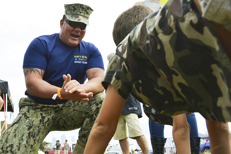 
              This Nov. 6. 2016 photo provided by the U.S. Navy shows Chief Petty Officer Joseph Schmidt III, assigned to the Navy SEAL and SWCC Scout Team, encouraging a young fan to do pushups at the 2016 Stuart Air Show in Stuart, Fla. The Navy is investigating Schmidt, a decorated SEAL who moonlights as a porn actor. The Naval Special Warfare Command is investigating whether Schmidt properly sought permission from his commanders for outside work, whether they condoned it and whether Schmidt engaged in behavior that discredits the service. (Petty Officer 2nd Class Pyoung K. Yi/U.S. Navy via AP)
            
