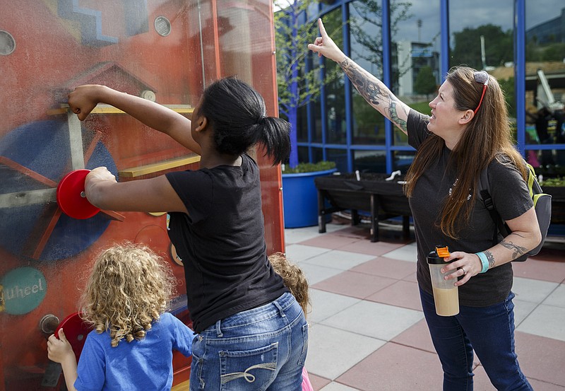 April Simington, right, shows one of her foster children, center, and her biological son, Delano, how to work an exhibit during a trip to the Creative Discovery Museum on Friday. Simington has taken in two sisters from foster care, which keeps the siblings together. Under state rules for foster children, their names or faces should not be used in news articles.
