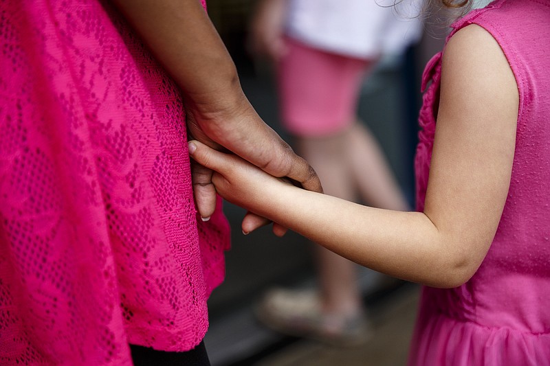 Lucy Simington, right, holds hands with one of her foster sisters during a trip to the Creative Discovery Museum on Friday, April 14, 2017, in Chattanooga, Tenn. Lucy's mother April Simington has taken on two sisters from foster care, which keeps the siblings together.  Under state rules for foster children, their names or faces should not be used in news articles.