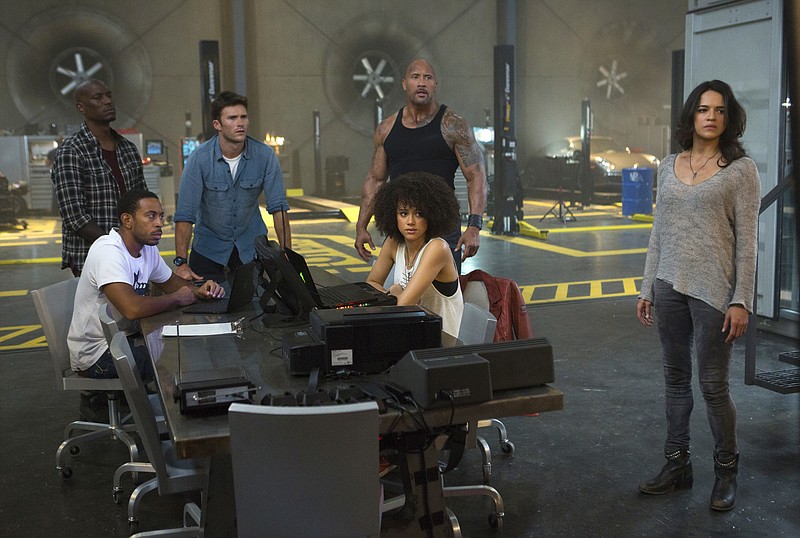 
              This image released by Universal Pictures shows, Chris "Ludacris" Bridges, seated left, and Nathalie Emmanuel, seated right, and Tyrese Gibson, standing from left, Scott Eastwood, Dwayne Johnson and Michelle Rodriguez in "The Fate of the Furious." (Matt Kennedy/Universal Pictures via AP)
            