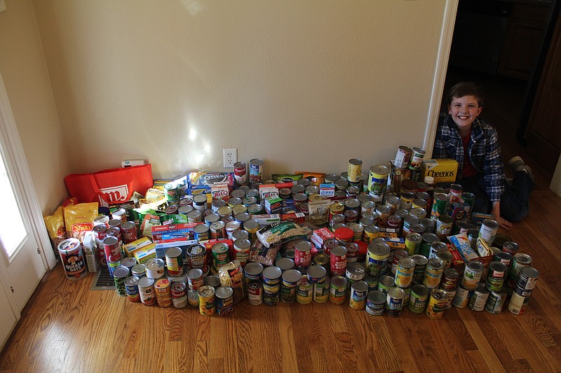 Soddy-Daisy Elementary student Ryan Jenkins sits with some of the food he collected as part of a food drive to benefit the Soddy-Daisy Food Bank.