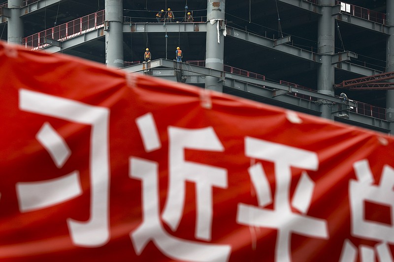 
              In this Sunday, April 16, 2017 photo, workers prepare to load cables at a building construction site as a propaganda banner reads "The Party Secretary General Xi Jinping" on display at the Central Business District in Beijing. China's economic growth ticked higher to 6.9 percent in the first quarter of the year, according to the latest figures.  The official data released Monday, April 17, 2017, show that the world's second-biggest economy grew at a slightly faster pace in the January-March period compared with the previous quarter's 6.8 percent expansion (AP Photo/Andy Wong)
            