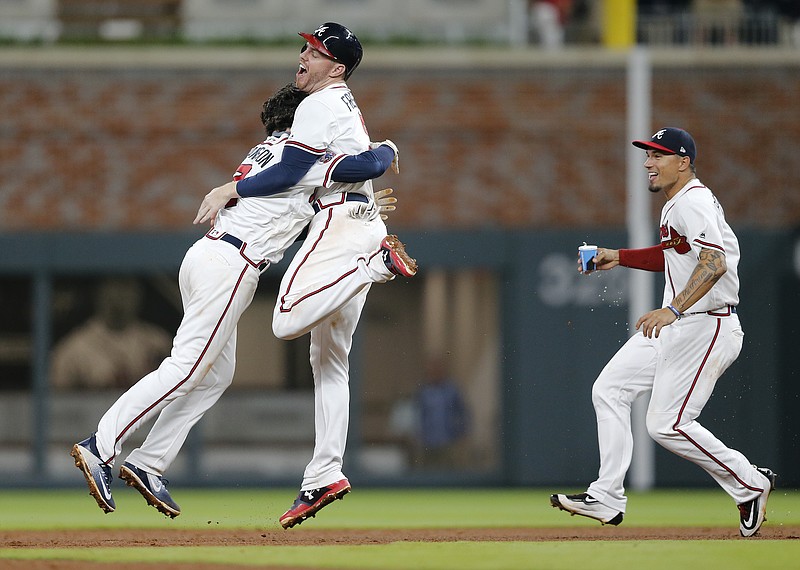 Atlanta Braves' Dansby Swanson, left, celebrates with Freddie Freeman as Jace Peterson rushes in after hitting a game-winning base hit in the ninth inning of a baseball game against the San Diego Padres, Monday, April 17, 2017, in Atlanta. Atlanta won 5-4. (AP Photo/John Bazemore)