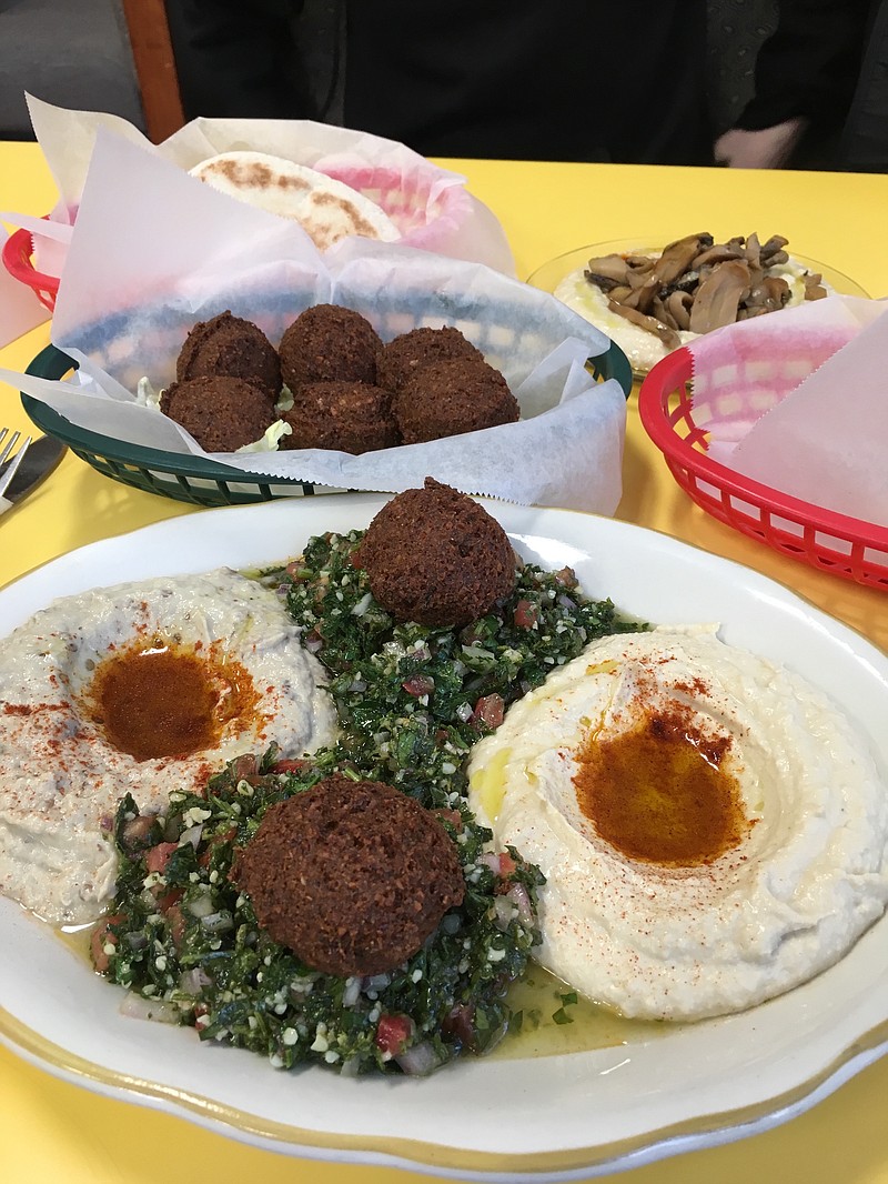 The Palestinian Plate includes, from left, babaganoush, tabouli topped with falafel and hummus. It is served with pita bread. In back are sides of falafel and mushrooms. (Photo by Cameron Morgan)