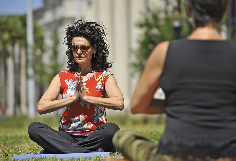 
              In this April 7, 2017. photo, County Court Judge Eleni Derke leads her yoga class on the lawn outside the Duval County Courthouse in Jacksonville, Fla. Derke is a certified yoga instructor. Derke holds her Yoga on the Lawn class once a month until the weather gets too hot. (Bob Self/The Florida Times-Union via AP)
            