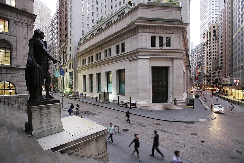 
              FILE - In this Oct. 8, 2014, file photo, people walk to work on Wall Street beneath a statue of George Washington, in New York. Global stock markets were mixed on Wednesday, April 19, 2017, as investors gauged the impact from British Prime Minister Theresa May's surprise decision to hold early elections. (AP Photo/Mark Lennihan, File)
            