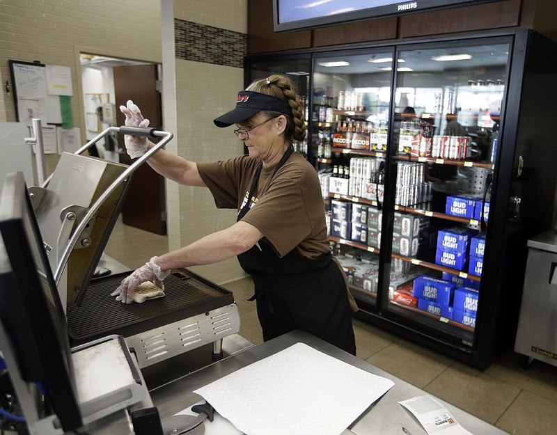 
              Barbra Thurman makes a burrito at Ricker's in front of the beer coolers in a convenience store in Sheridan, Ind., Wednesday, April 19, 2017. The location is one of two that one gas station owner discovered a loophole in the law that allows them to sell cold beer. The location has installed limited seating and sells reheated burritos, landing a restaurant classification and the right to sell cold beer. (AP Photo/Michael Conroy)
            