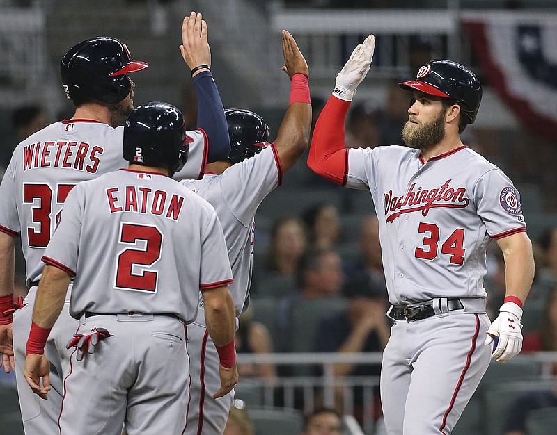 
              Washington Nationals' Bryce Harper gets high-fives at home hitting a grand slam off Atlanta Braves pitcher Julio Jones during the second inning of a baseball game Wednesday, April 19, 2017, in Atlanta. Harper had a solo homer in the first inning. (Curtis Compton/Atlanta Journal-Constitution via AP)
            