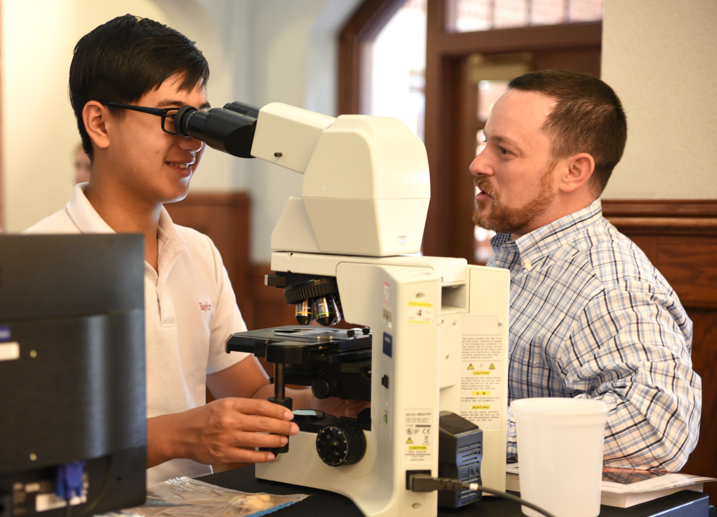 Jacky Li, left, looks through the microscope as he talks with Dr. Paul Kaplan, pathologist with CHI Memorial, Thursday, April 20, 2017 at Baylor. Students had the opportunity to sit at the controls of the da Vinci Surgical System.