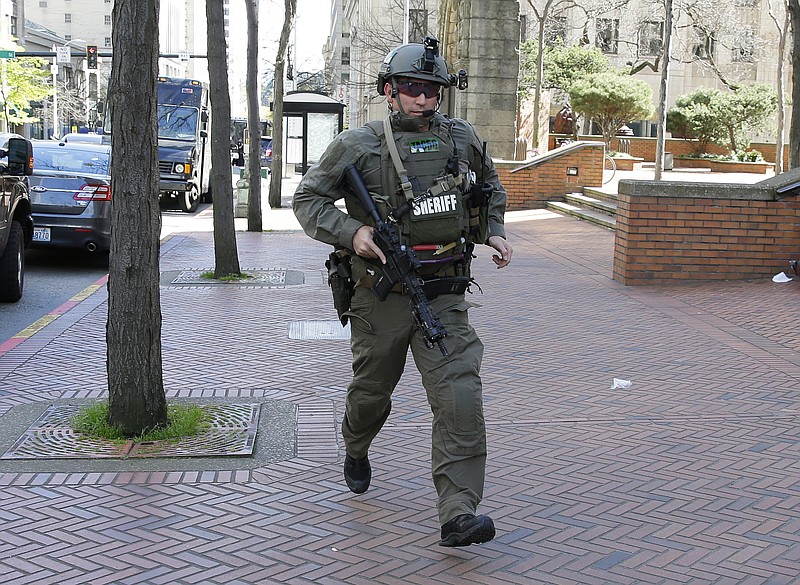 
              A King County Sheriff's Deputy carries a gun as he runs near the scene of a shooting involving several police officers in downtown Seattle, Thursday, April 20, 2017. (AP Photo/Ted S. Warren)
            
