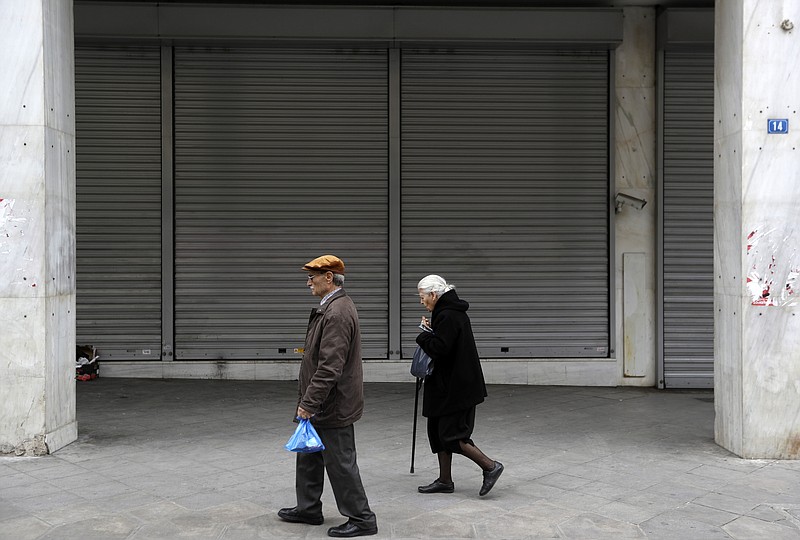 
              An elderly couple pass a closed bank in Athens, Friday, April 21, 2017. Greece’s independent statistics agency says the country has posted a high primary budget surplus in 2016, at 3.9 percent of gross domestic product. (AP Photo/Thanassis Stavrakis)
            