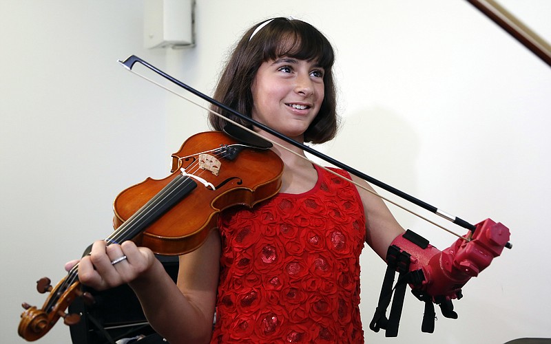 
              Ten-year-old Isabella Nicola Cabrera smiles after playing her violin with her new prosthetic at the engineering department of George Mason University in Fairfax, Va., Thursday, April 20, 2017. "Oh my gosh, that's so much better," Isabella said as she tried out the new prosthetic. (AP Photo/Steve Helber)
            