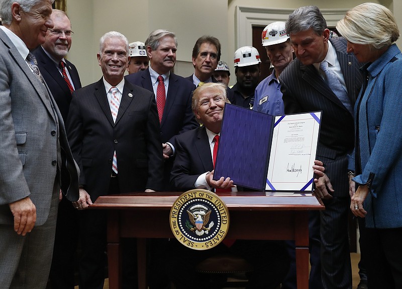 
              FILE - In this Feb. 16, 2017 file photo, Sen. Shelley Moore Capito, R-W. Va., right, Sen. Joe Manchin, D-W. Va., second from right, and coal miners, watch as President Donald Trump holds up H.J. Res. 38 after signing it in the Roosevelt Room of the White House in Washington. Lawmakers from coal-mining states are pushing to extend health benefits for more than 22,000 retired miners and widows whose live-saving medical coverage is set to expire at the end of April.  (AP Photo/Carolyn Kaster, File)
            