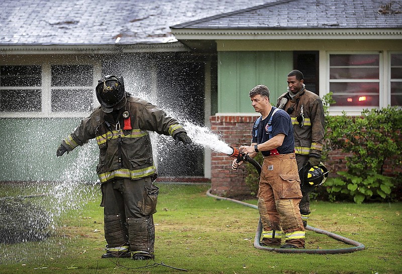 
              Memphis firefighter Jeremy Chastain, left, is hosed down in front of Elvis Presley's former home which caught fire damaging the house, Saturday, April 22, 2017, in Memphis, Tenn. Presley purchased the home in 1956. The Commercial Appeal says Rhodes College looks after the house, now owned by music industry veteran and philanthropist Mike Curb. (Jim Weber/The Commercial Appeal via AP)
            
