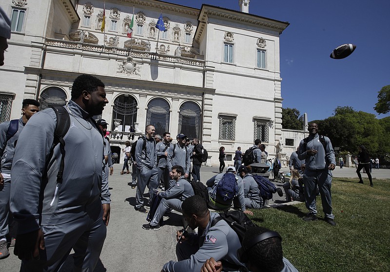 
              Michigan football team players stand in Rome's Villa Borghese park, Sunday, April 23, 2017. Michigan's football team arrived in Rome this weekend and kicked off the unique trip by meeting with refugees before going to the Vatican for a Papal address and practicing a few times. (AP Photo/Alessandra Tarantino)
            