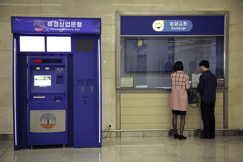 
              In this April 11, 2017 photo, a man and woman stand at a counter next to a Ryugyong Commercial Bank automated teller machine at the Sunan International Airport in Pyongyang, North Korea. No modern airport terminal is complete without an ATM, and Pyongyang’s now has two. But they don’t work, because of new Chinese sanctions, according to bank officials, and it’s not clear when they will. ATMs are an alien enough concept in North Korea that those in the capital’s shiny new Sunan International Airport have a video screen near the top showing how they work and how to set up an account to use them. The explanatory video is in Korean, but the machines, which are meant primarily for Chinese businesspeople and tourists, don’t give out cash in the North Korean currency. (AP Photo/Wong Maye-E)
            