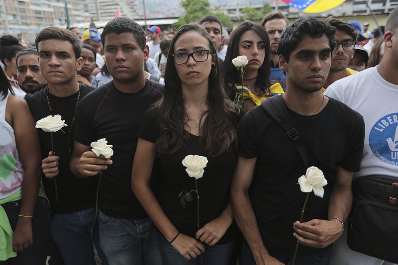 
              Protesters in black carry white flowers during a silent protest in homage to the at least 20 people killed in unrest generated after the nation's Supreme Court stripped congress of its last powers, a decision it later reversed, outside the Venezuelan Episcopal Conference in Caracas, Venezuela, Saturday, April 22, 2017. Saturday's protest is the latest mass gathering in a wave of tumult that has rocked the nation over the last three weeks as demonstrators continue to press for new elections. (AP Photo/Fernando Llano)
            