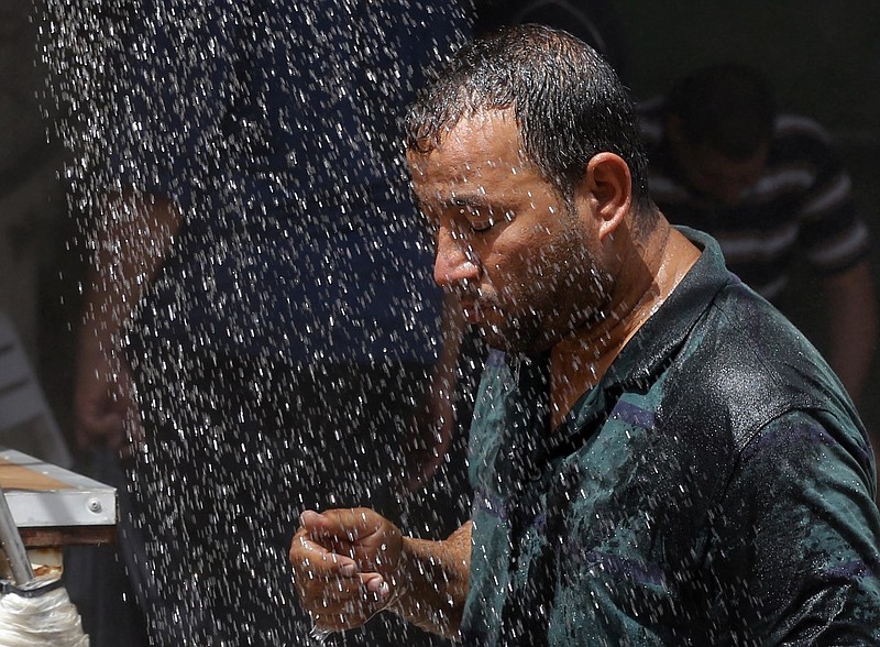 
              FILE - In this July 20, 2016 file photo, an Iraqi man cools off the summer heat by using an open air shower in Baghdad, Iraq. Most people on Earth have already felt extreme and record heat, drought or downpours goosed by man-made global warming, a new study finds.  (AP Photo/Karim Kadim, File)
            