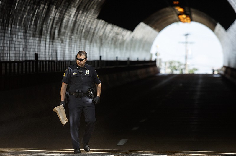 Chattanooga police Sgt. Steve Wiertel searches for evidence after a shooting temporarily closed the westbound lane of  the Brainerd Tunnel on Tuesday, April 25, 2017, in Chattanooga.