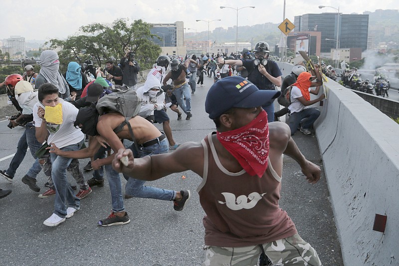 
              Anti-government protesters throw stones from a highway overpass at a passing police patrol in Caracas, Venezuela, Monday, April 24, 2017. Thousands of opponents to President Nicolas Maduro shut down main roads around the country as the protest movement against his administration is entering its fourth week. (AP Photo/Fernando Llano)
            