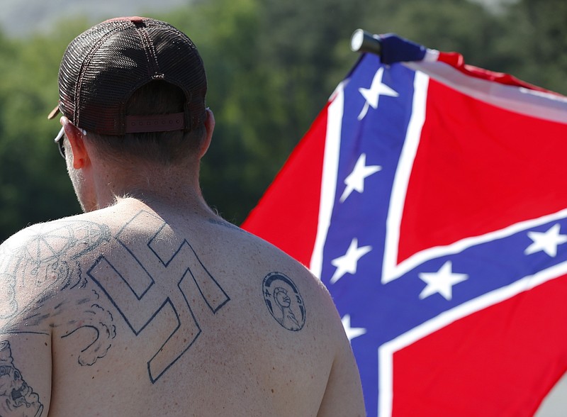 
              FILE - In this April 23, 2016 file photo, a man walks during a protest at Stone Mountain Park, in Stone Mountain, Ga.  Extremist groups are joining together with a shared goal for whites. A new Ku Klux Klan alliance formed in March 2017 has united chapters from around the country, and a consortium of organizations composed of white nationalists and white separatists is marking its first anniversary. Watchdog groups say white extremists typically can’t work together because of jealousy and infighting. But leaders say they’re united as never before.  (AP Photo/John Bazemore)
            