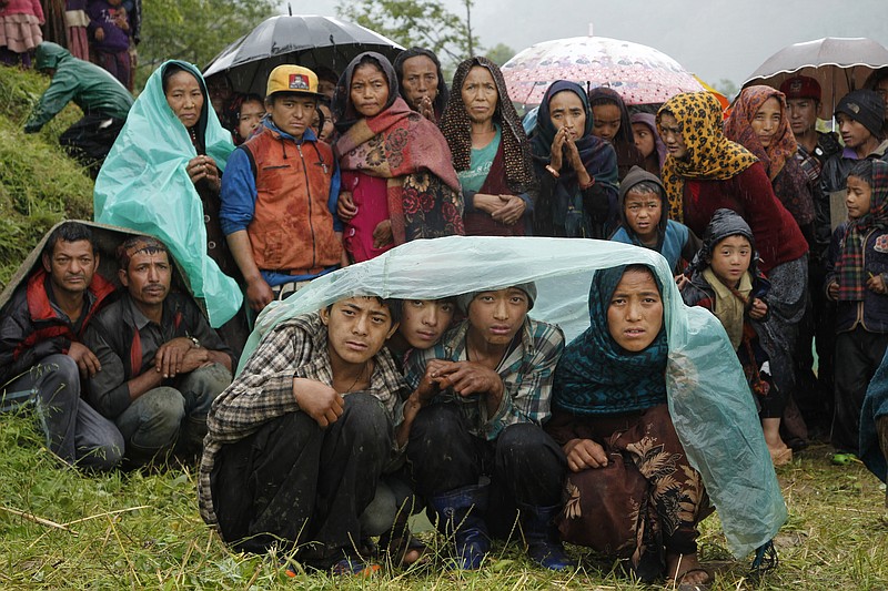 
              FILE - In this April 29, 2015 file photo, villagers wait in the rain as an aid relief helicopter lands at their remote mountain village of Gumda, Nepal. Nearly everything was lost two years ago, when a terrifying earthquake rattled the Himalayan nation on April 25, 2015, killing more than 9,000 people and toppling nearly a million homes nationwide. The government has been criticized for moving slowly in dispersing funds that would allow people to rebuild on their own. (AP Photo/Wally Santana, File)
            