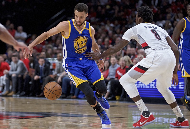 Golden State Warriors guard Stephen Curry, left, dribbles around his back past Portland Trail Blazers forward Al-Farouq Aminu during the first half of Game 4 of an NBA basketball first-round playoff series, Monday, April 24, 2017, in Portland, Ore. (AP Photo/Craig Mitchelldyer)