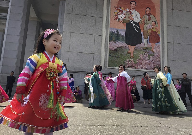 A young girl watches as North Korean men and women take part in a mass dance on Tuesday, April 25, 2017, in Pyongyang, North Korea. Pyongyang residents hold mass dances across the city to mark the 85th anniversary of the country's army. Despite deepening tensions on the Korean Peninsula, and reports of a major military drill on the country's east coast, the North's capital was quiet. (AP Photo/Eric Talmadge)