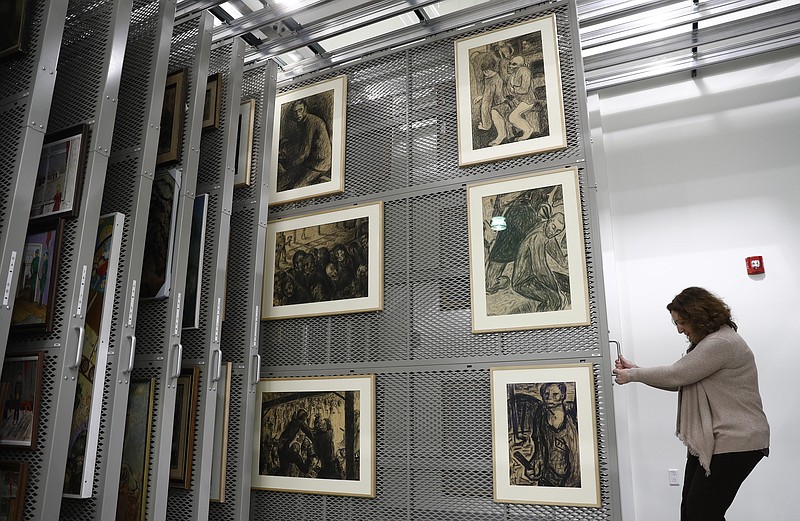 
              Laura Seylar, registrar of Collections Management, slides open a section of the art rack at the U.S. Holocaust Memorial Museum's David and Fela Shapell Family Collections, Conservation and Research Center in Bowie, Md., Monday, April 24, 2017. The art racks holds painting and other hanging art made during the period or the Holocaust and works showing memories of the Holocaust made by survivors.The Shapell Center is a new state-of-the-art facility that will house the collection of record of the Holocaust. (AP Photo/Carolyn Kaster)
            