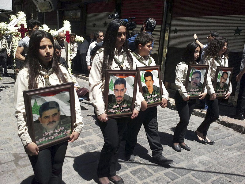 
              In this photo released by the Syrian official news agency SANA, girls carry the pictures of five Syrian men who were kidnapped four years ago from the historic town of Maaloula near Damascus by al-Qaida-linked militants, during their funeral prayers in Bab Touma, a predominantly Christian quarter of the Syrian capital Damascus, Syria, Tuesday, April 25, 2017. The remains of the five Christians were discovered recently by the Lebanese army in a remote area near the Lebanese-Syrian border and handed over to Syrian authorities on Monday. (SANA via AP)
            