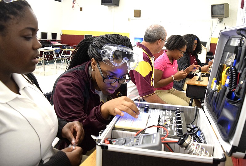 Tyner students (from left) Jada Beckett and Takayla Sanford work on buidling circuits on the digital analog trainer, while teacher Bryan Robinson instructs Brookeana Willams and Noemy Marberry about soldering. Tyner High teacher Bryan Robinson has started a mechatronics program that offers student the opportunity to graduate with a specific certification that will aid them in finding jobs with high-tech companies.