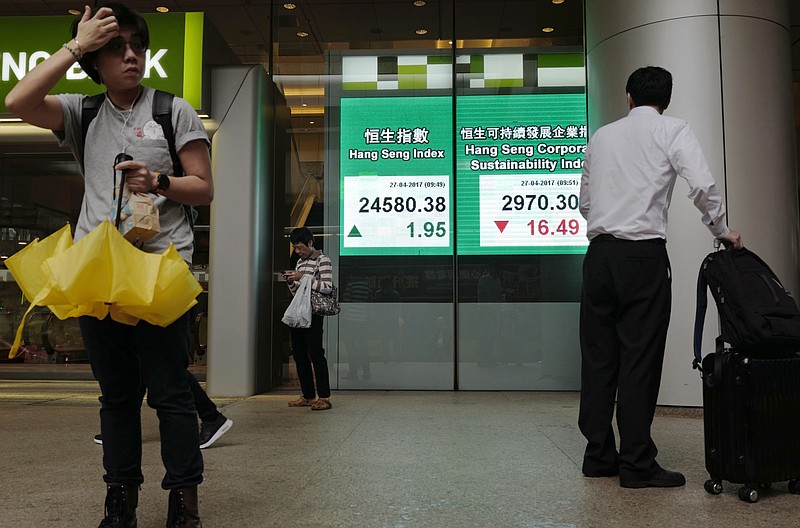 
              People stand next to an electronic board showing Hong Kong share index outside a local bank in Hong Kong, Thursday, April 27, 2017. Share prices were mostly lower in Asia following U.S. President Donald Trump’s proposal for tax cuts, with Japan’s Nikkei 225 index down 0.2 percent and Hong Kong’s Hang Seng 0.3 percent lower. Traders were awaiting the release of a policy statement by the Bank of Japan, though no major changes were expected. (AP Photo/Vincent Yu)
            