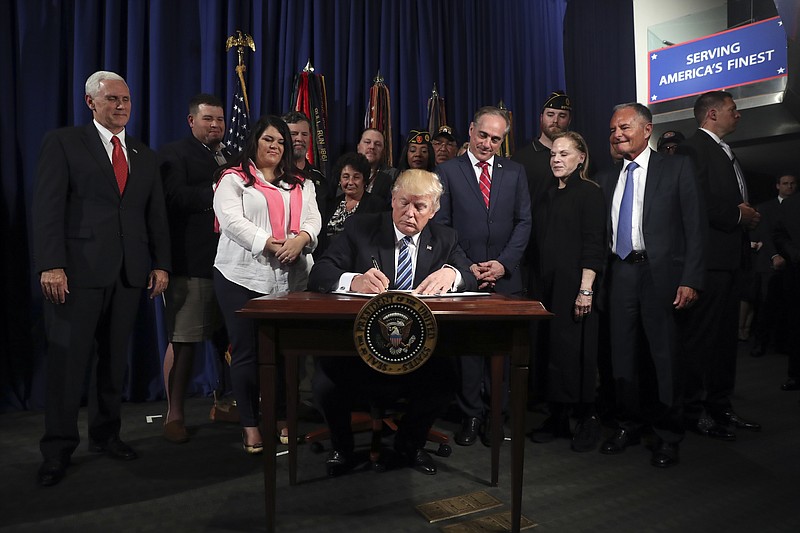 
              President Donald Trump signs an Executive Order on "Improving Accountability and Whistleblower Protection" at the Department of Veterans Affairs, Thursday, April 27, 2017, in Washington. (AP Photo/Andrew Harnik)
            