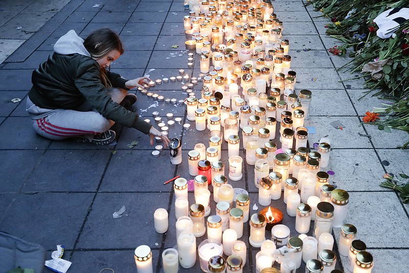 
              FILE- In this file photo dated Sunday, April 9, 2017, a girl lights candles in response after a highjacked truck was driven into a crowd of pedestrians and crashed into a department store in Stockholm, Sweden.  A woman in her 60s who was injured in the April 7 truck attack in Stockholm has died, Swedish authorities said Friday April 28, 2017, raising the death toll to five.(AP Photo/Markus Schreiber, FILE)
            