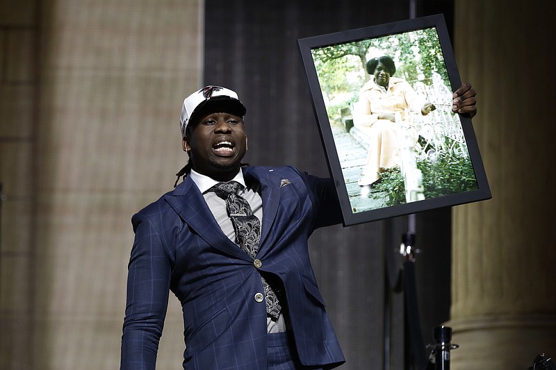 Takkarist McKinley carries a photograph of his grandmother on the stage after being selected by the Atlanta Falcons during the first round of the NFL draft this past Thursday night in Philadelphia. The former UCLA defensive end said he is motivated by the memory of Myrtle Collins and what she did for him during his troubled childhood.