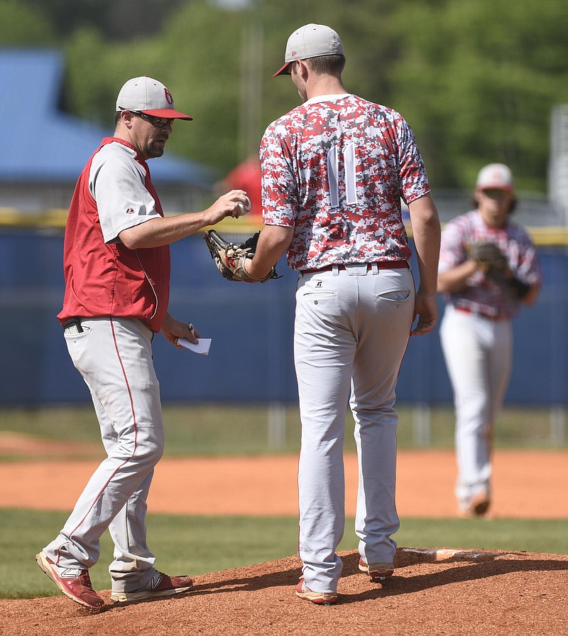 Ooltewah baseball coach Brian Hitchcox hands the ball to relief pitcher Landon Elrod during a District 5-AAA tournament game last season. Hitchcox would like to see the TSSAA change its format for the baseball postseason.