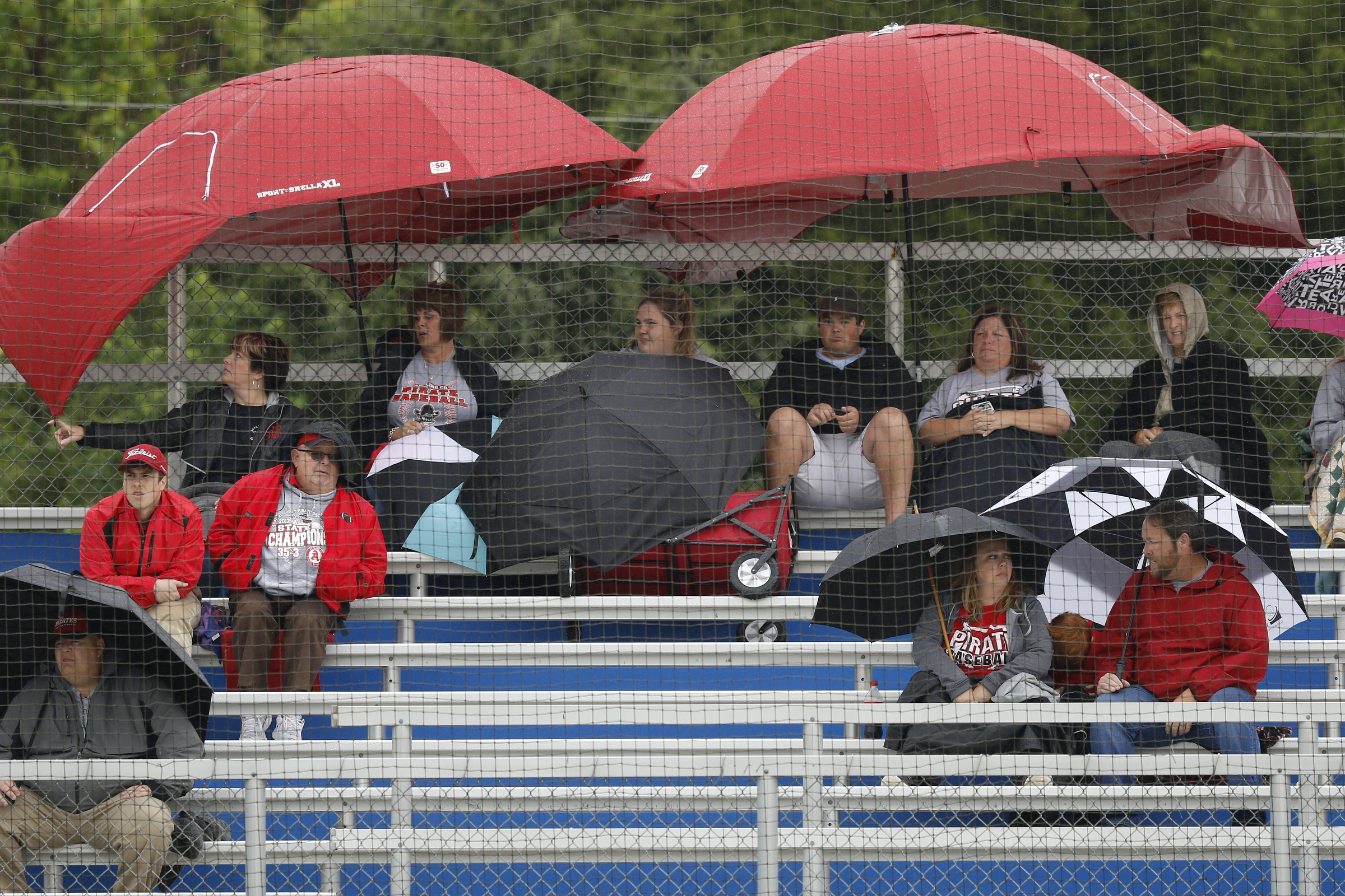 Appling County baseball fans sit beneath umbrellas in pouring rain during Friday's Class AAA state playoff game at Ringgold High School. The teams played through four innings — which included a weather delay — before umpires stopped play for good, meaning the game is unofficial and must be started over.