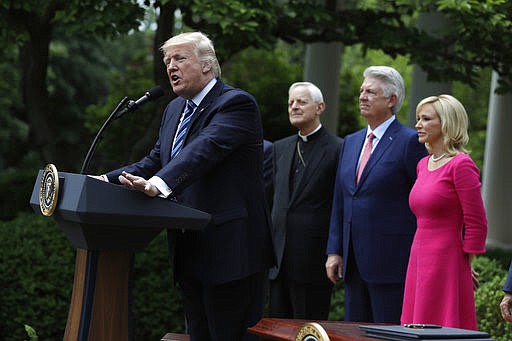 President Donald Trump speaks in the Rose Garden of the White House in Washington, Thursday, May 4, 2017, before signing an executive order aimed at easing an IRS rule limiting political activity for churches. From second from left are, Cardinal Donald Wuerl is the Archbishop of Washington, Pastor Jack Graham, and Paula White, senior pastor of New Destiny Christian Center in Apopka, Fla. (AP Photo/Evan Vucci)
