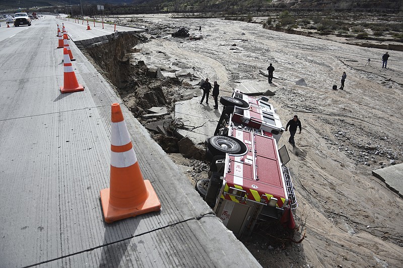 
              FILE - In this Feb. 18, 2017 file photo, officials look over the scene at Interstate 15 in the Cajon Pass, Calif., where part of the freeway collapsed due to heavy rain. A state $5 billion annual plan raises fuel taxes and vehicle fees to pay for repairs to state and local roads, while also providing money for public transit and biking and walking trails. (David Pardo/The Daily Press via AP, file)
            