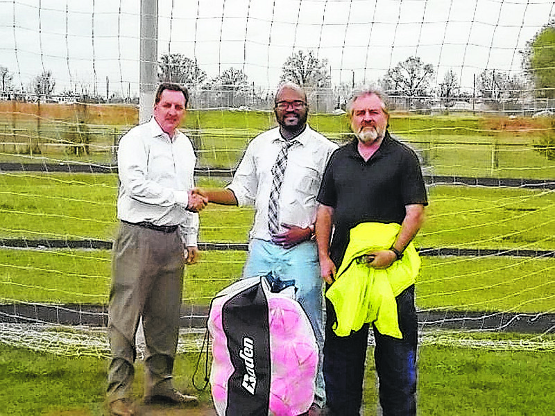 George Coogan, left, brings new soccer balls purchased with funds donated by fellow Baylor soccer parents to Howard School soccer coach Curtis Warner, center, and assistant coach Clive Bonnick.